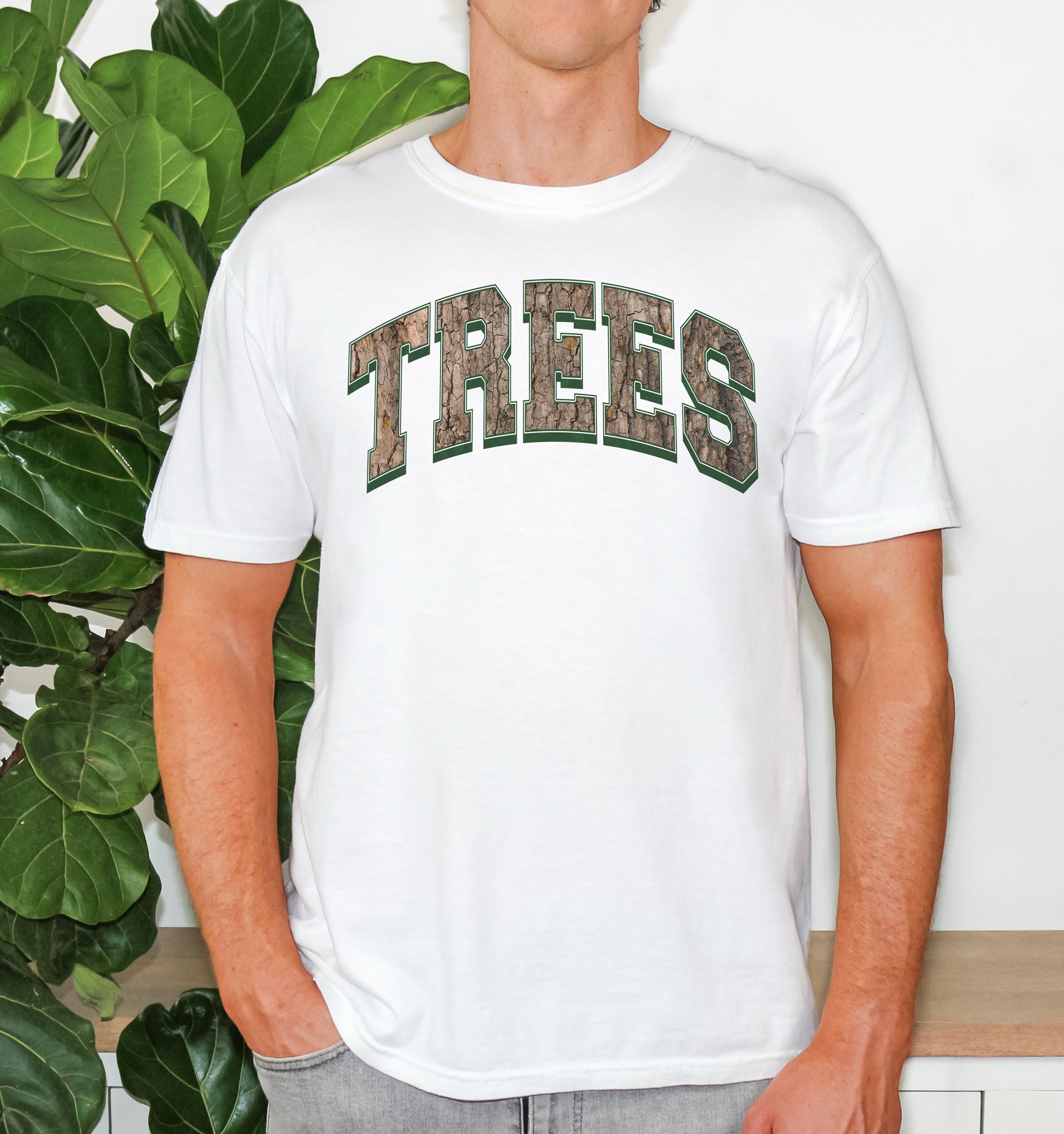 Unisex Comfort Colors t-shirt in white with Trees graphic design in a camo, worn by a model to display relaxed fit